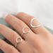 Hand with three open circle sterling silver rings (small, medium, large with hammered finish) on soft background.

